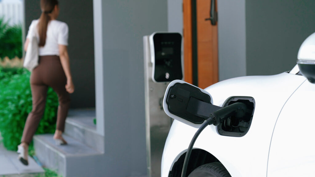 Progressive lifestyle of a modern woman who have just returned from work in an electric vehicle that is being charged at home Electric vehicle powered by sustainable clean energy